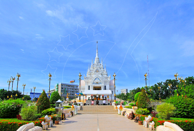 White ornate Thai city pillar shrine with tall spire, framed by manicured gardens, lamp posts and elephant statues
