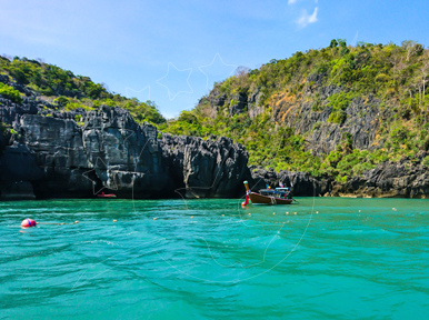 Turquoise lagoon ringed by jungle-topped limestone cliffs with longtail boats moored and red buoys floating