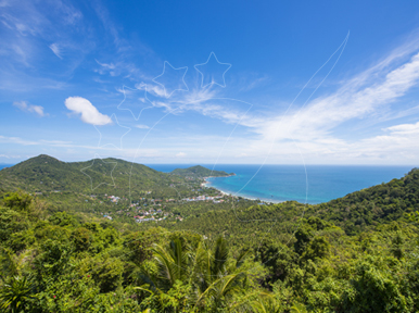 Hilltop viewpoint over jungle hills to a turquoise bay, coastal village and blue sky with wispy clouds