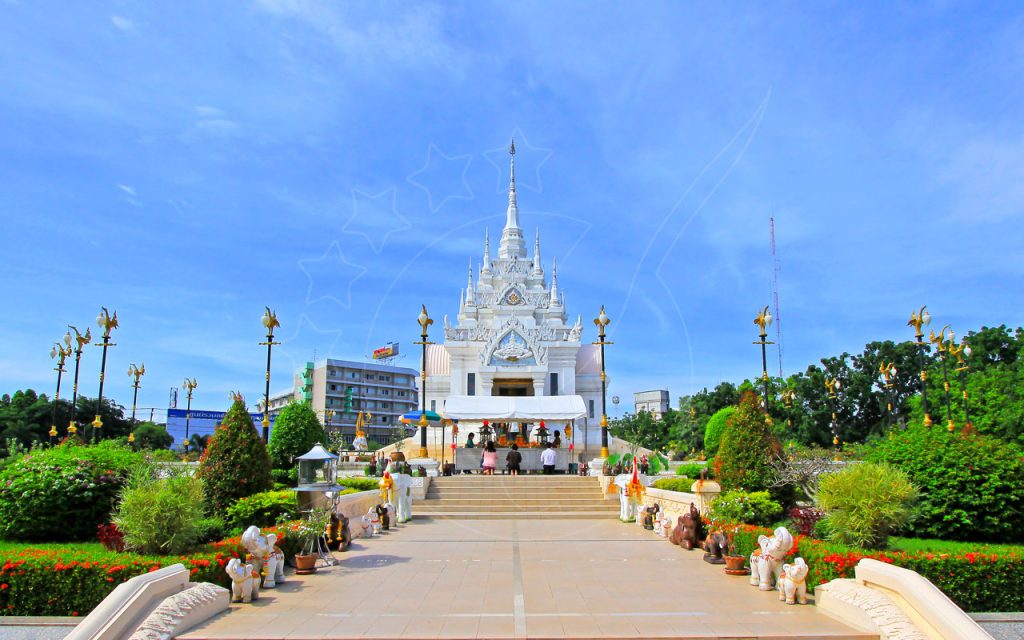 Ornate white Thai city pillar shrine with spires, elephant statues, and manicured gardens under blue sky