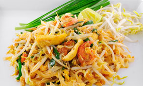 Pad Thai noodles with shrimp, egg, fresh bean sprouts, spring onions and a lime wedge on a white plate