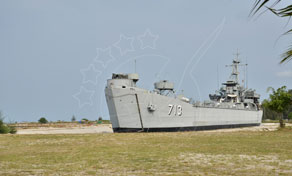 Decommissioned grey navy warship with hull number 73 sitting on grass as a land-based memorial