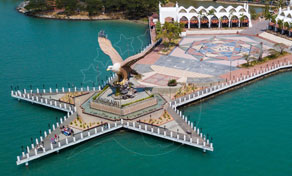 Aerial view of a giant eagle sculpture on a star-shaped white pier beside turquoise sea, Langkawi