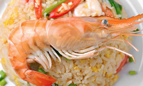 Whole cooked prawn served on a plate of Thai fried rice with chilli, tomato and spring onion