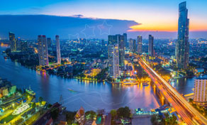 Aerial dusk view of Bangkok skyline with illuminated high-rises, the Chao Phraya River and a lit bridge