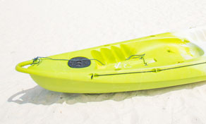 Bright lime-green plastic sit-on-top kayak resting on white sand at a beach