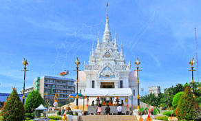 White Thai city pillar shrine with tall ornate spire under blue sky, flanked by gold lamp posts and gardens