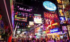Crowds fill a neon-lit nightlife street at night, lined with bar and club signs — Walking Street, Pattaya, Thailand