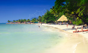 Tropical beach with palm trees, thatched sun shelter, loungers and turquoise shallow water under clear blue sky