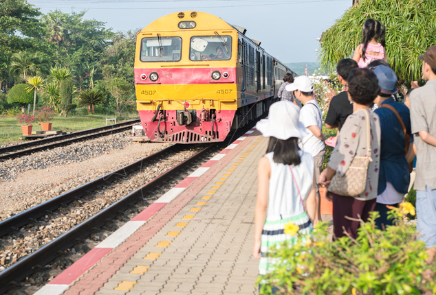 Yellow and red diesel locomotive no. 4507 approaching a station platform as travellers wait beside the tracks