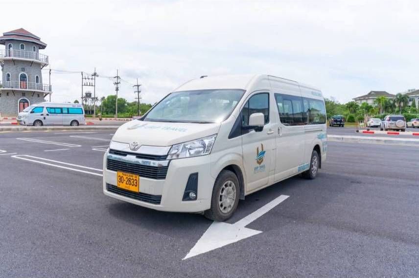 Weißer Toyota Hiace Touristen-Minivan mit thailändischem Kennzeichen auf leerem Asphaltplatz bei bewölktem Himmel