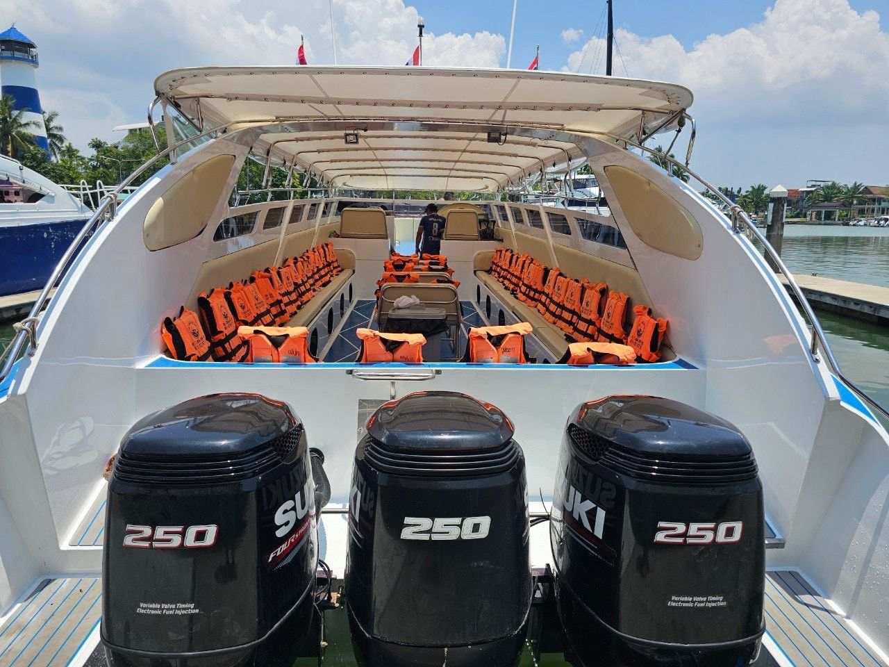 Heckansicht eines überdachten Speedboots mit drei Suzuki 250 Außenbordern und orangen Schwimmwesten im Hafen