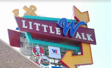 Vintage neon sign for Little Walk establishment with turquoise and purple lettering and decorative roofline ornaments