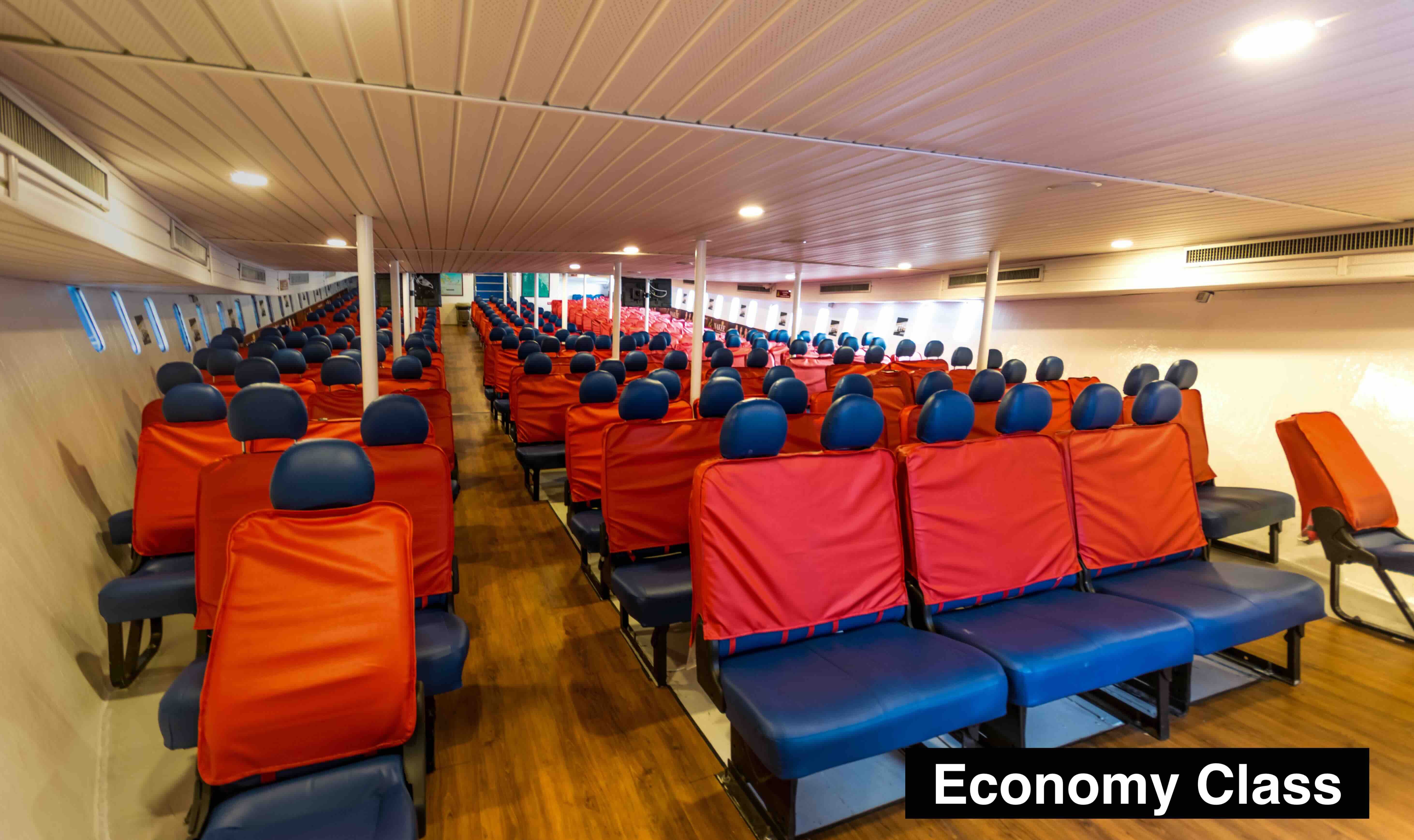 Empty economy class cabin of a passenger ferry with rows of blue seats and red seat covers