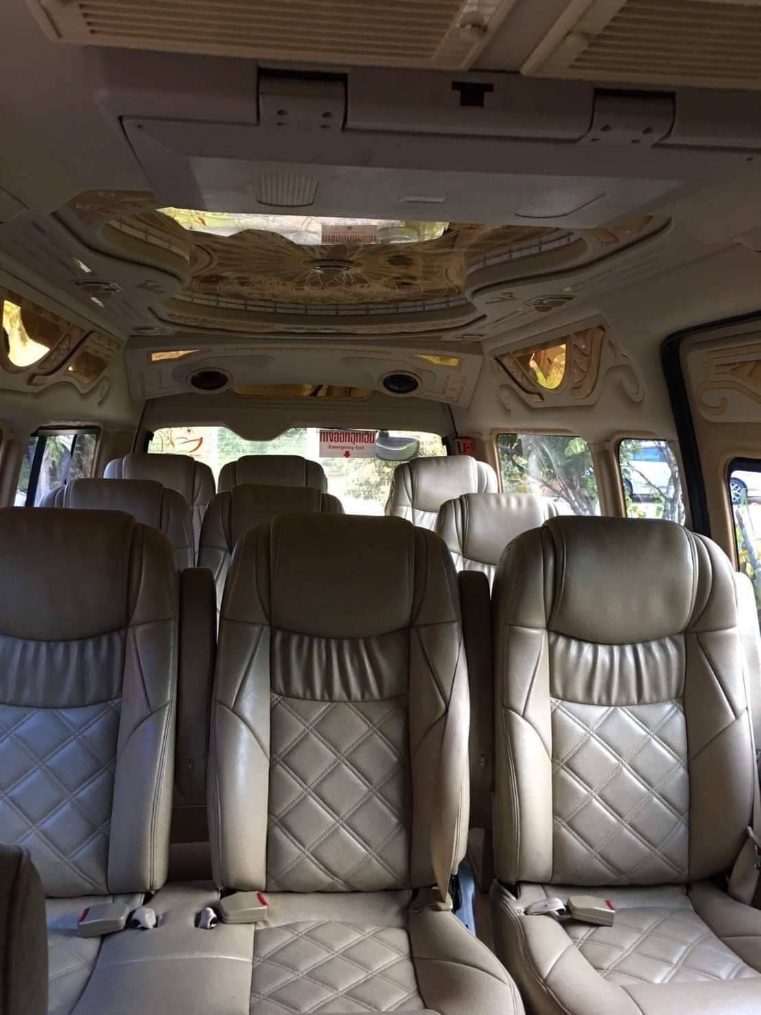 Innenraum eines Thai-Minivans mit beigen Steppledersitzen, dekorativen Deckenpaneelen und Thai-Notausgangsschild