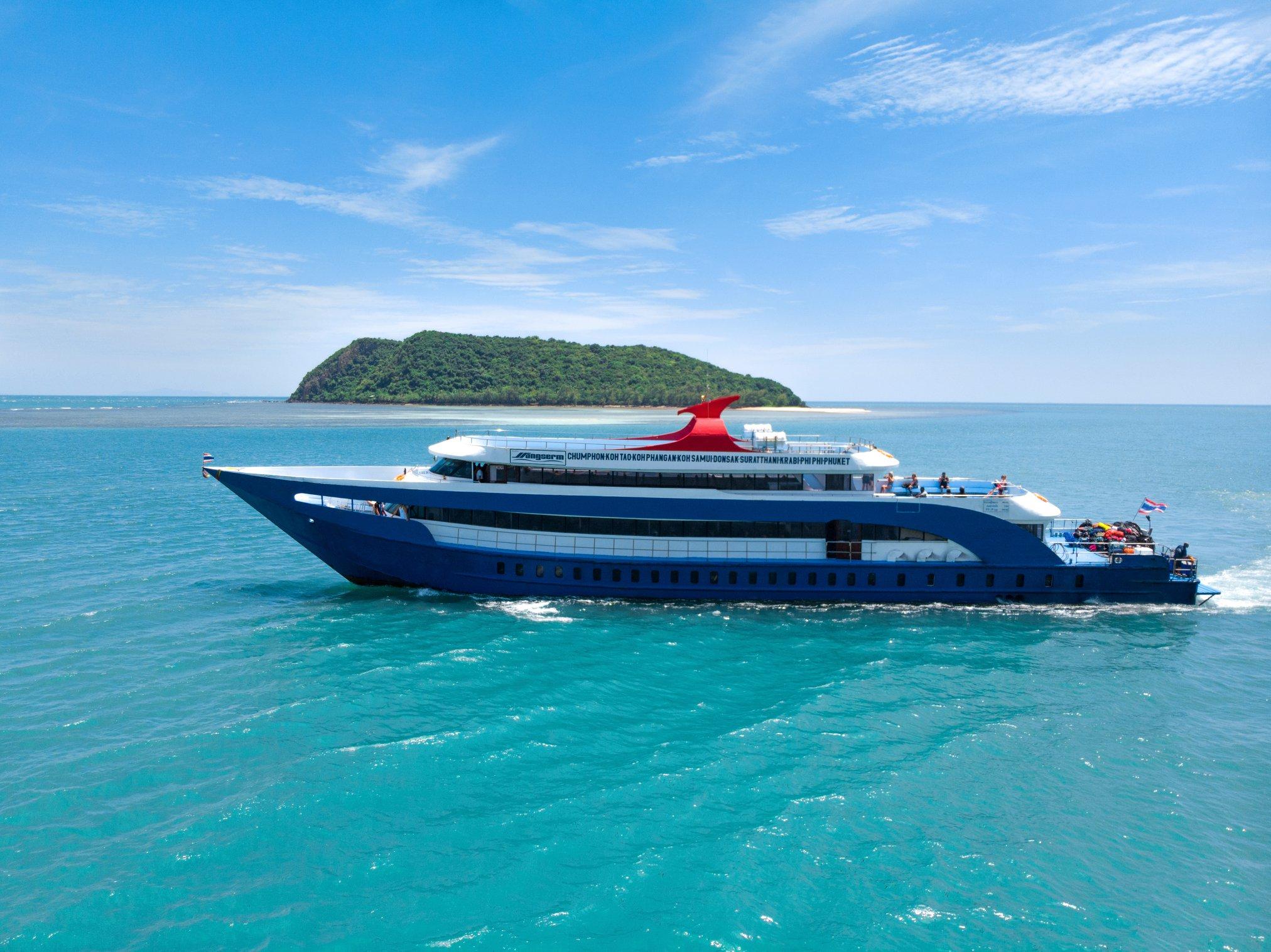 Blue and white Songserm passenger ferry cruising turquoise sea past a small green island under blue sky in Thailand