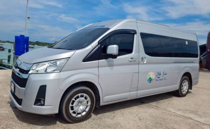 Silver Toyota Hiace passenger minivan parked on a coastal pier transfer area under bright daylight