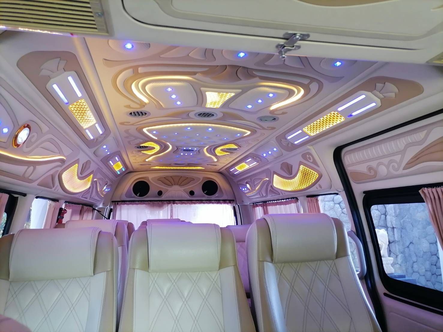مقصورة فان VIP بسقف منحوت مزخرف وإضاءة LED ومقاعد جلدية كريمية وستائر وردية