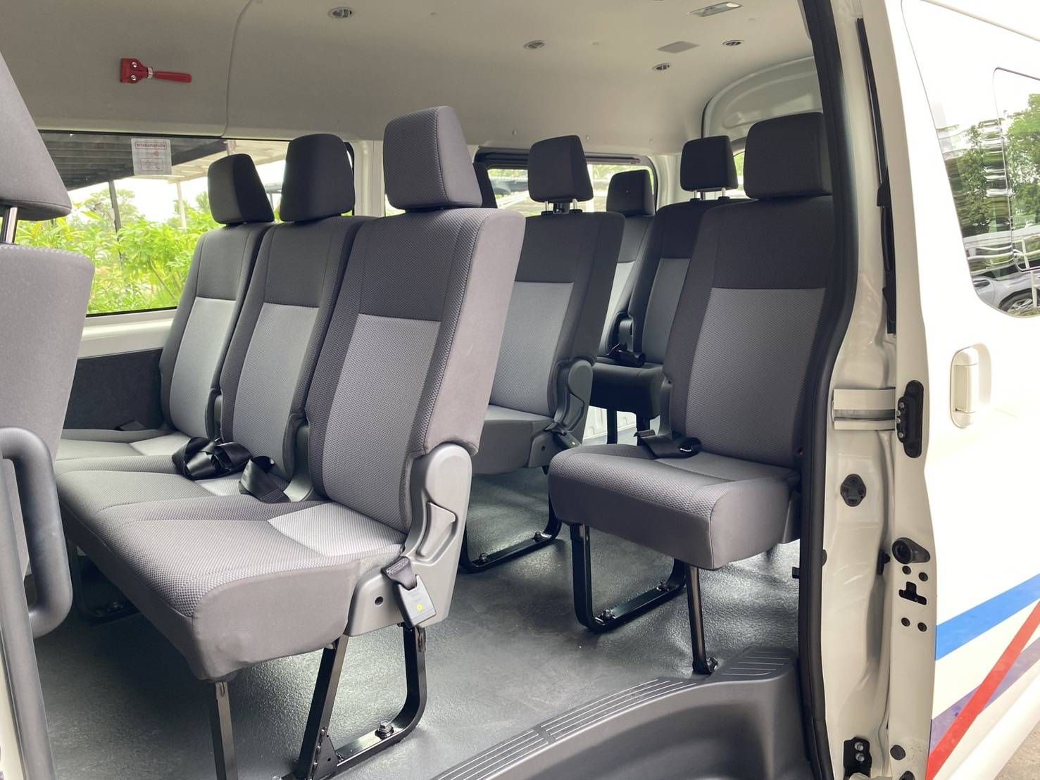 Leere graue Stoffsitze in einem weißen Passagier-Minivan, gesehen durch die offene Schiebetür